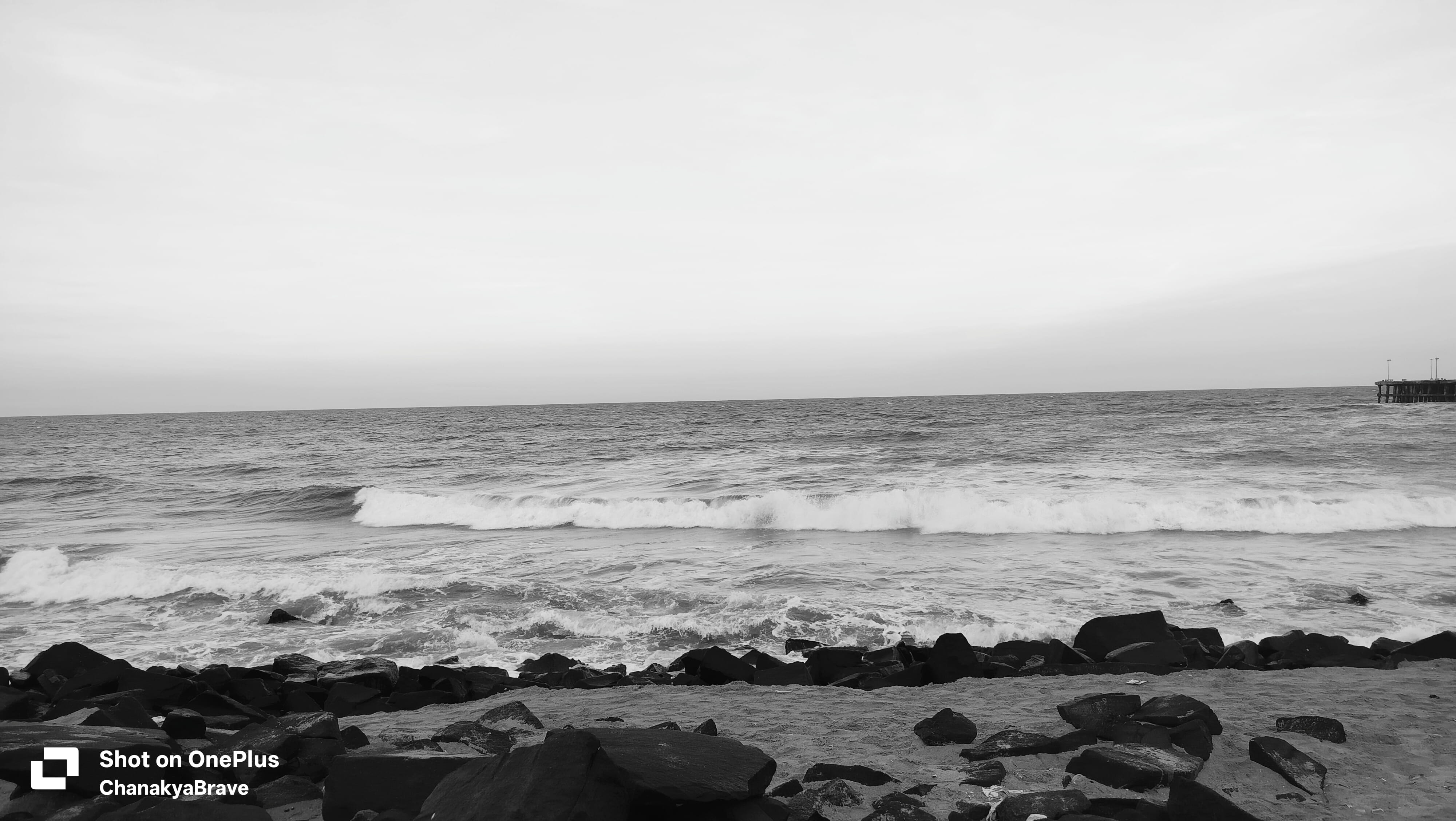 Waves breaking over dark rocks along a sandy coastline