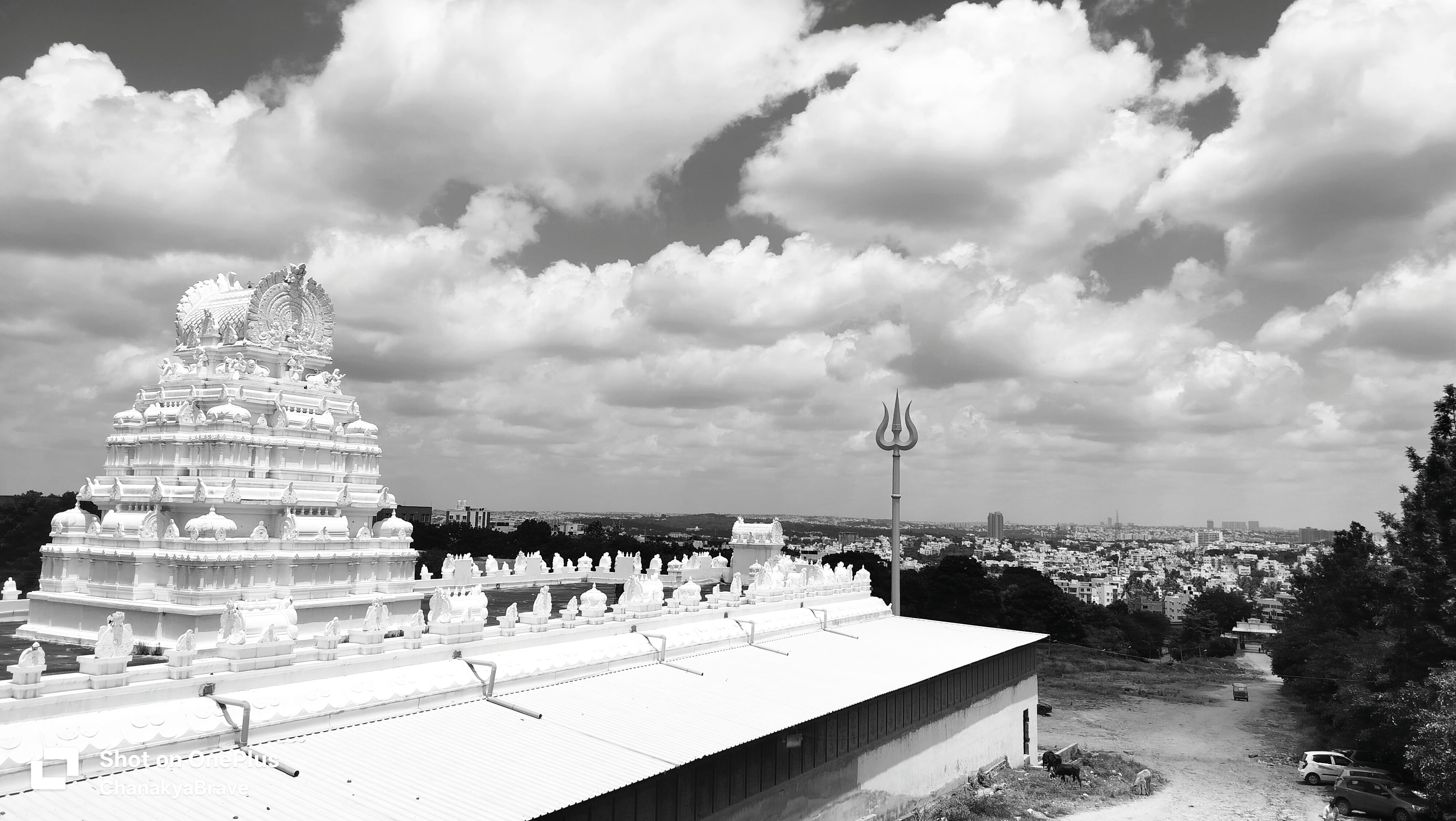 A white temple tower and trishula overlooking a sprawling city skyline